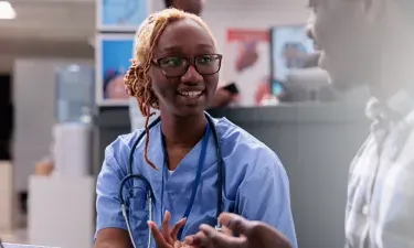 Virginia medical assistant smiling and discussing treatment with patient in clinic