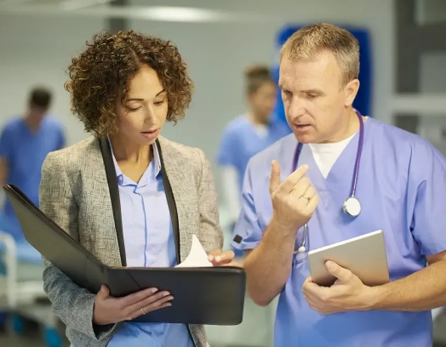 Healthcare manager reviewing meeting notes with registered nurse in hospital